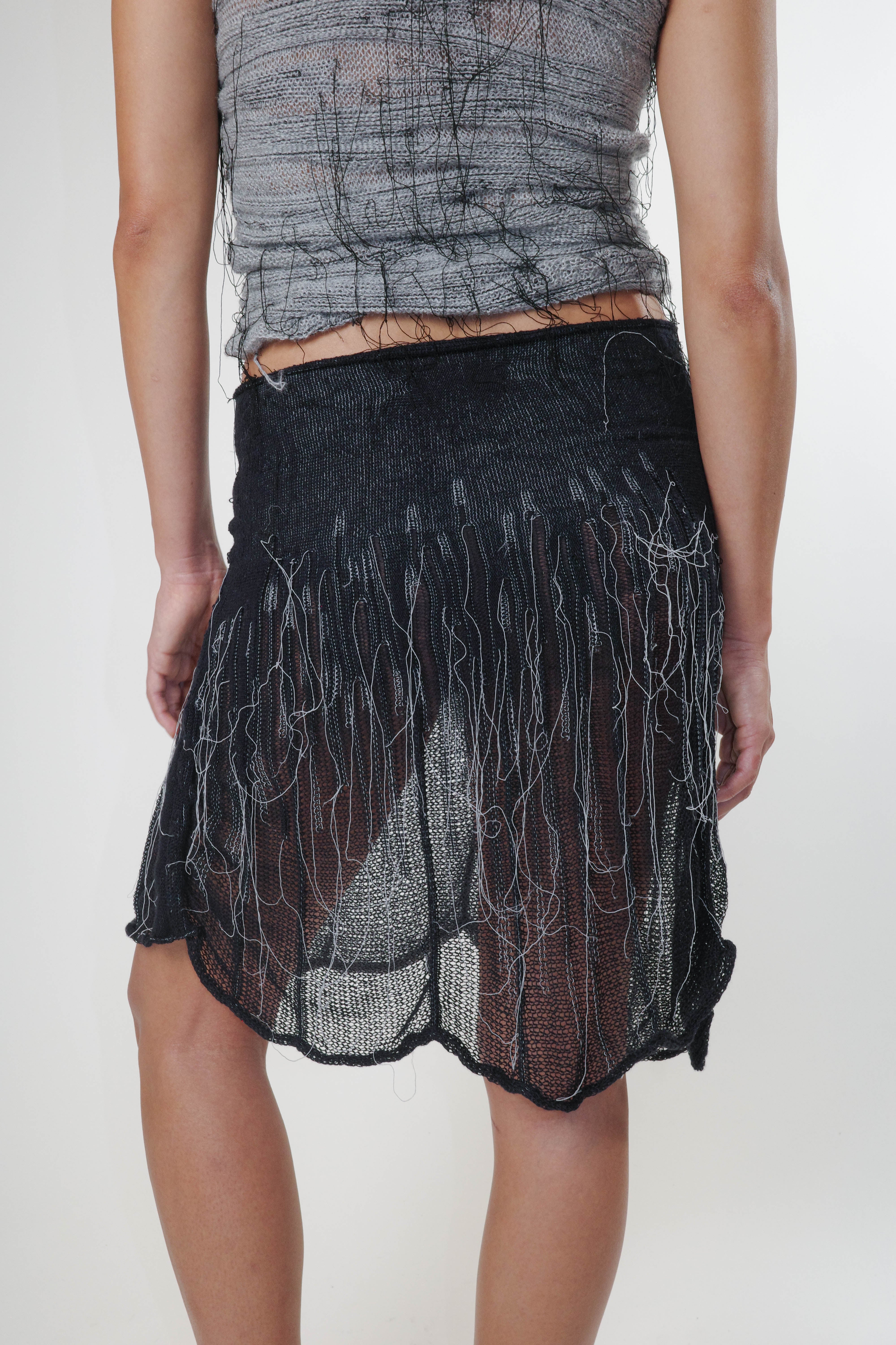 Black knit piece with organic detailing, styled as a skirt, lightweight and semi sheer