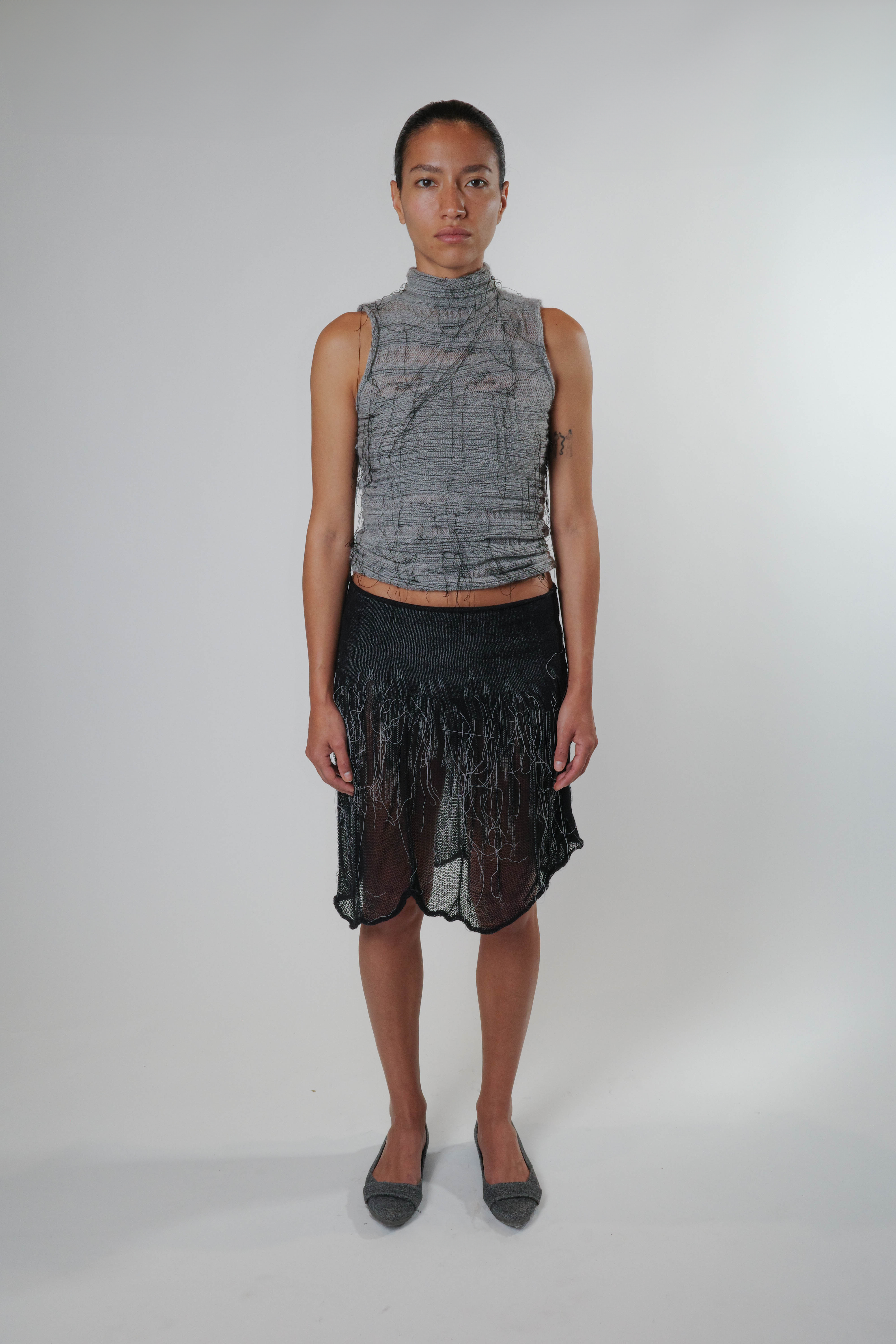 Black knit piece with organic detailing, styled as a skirt, lightweight and semi sheer