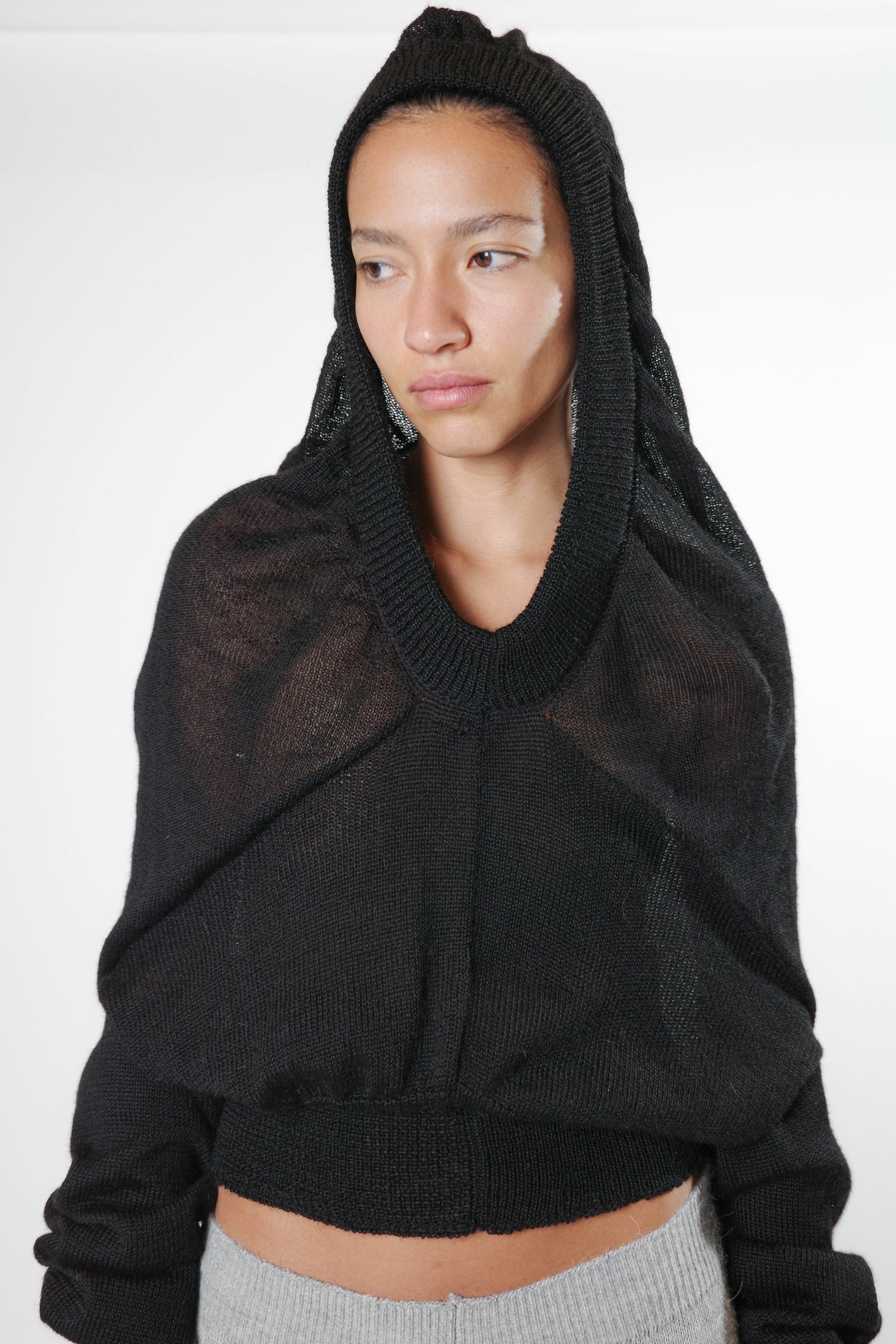 100% baby alpaca black knit triangle hoodie with soft hood, sculptural drape, and ribbed hem, close up front view
